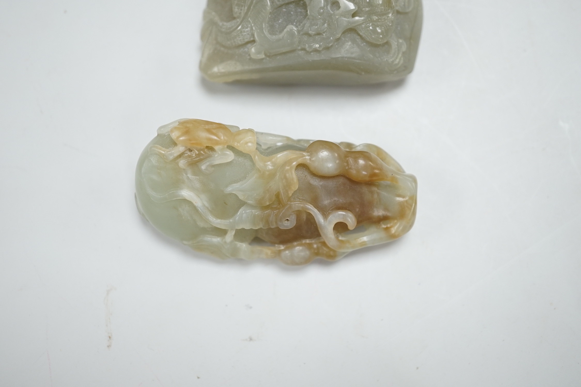 A Chinese green and russet green and brown jade carving of gourd and a green jade pebble carved in relief with a dragon, largest 6.5cm high (2)